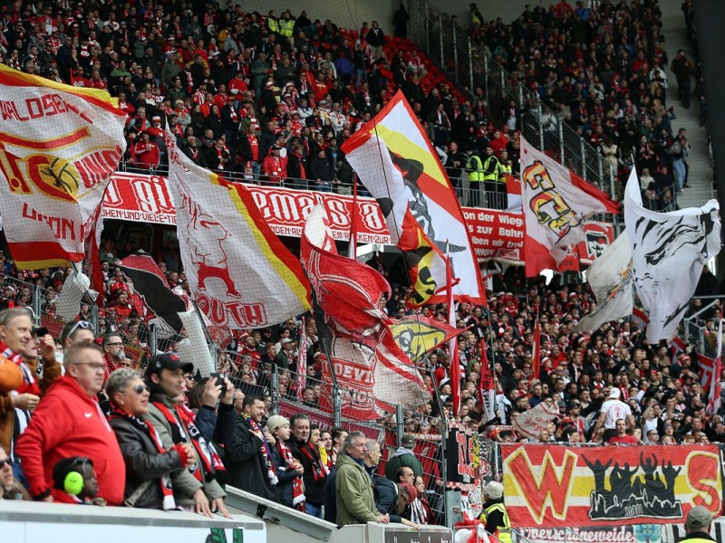 Fans von Union Berlin schwenken im Stadion die Fahnen.