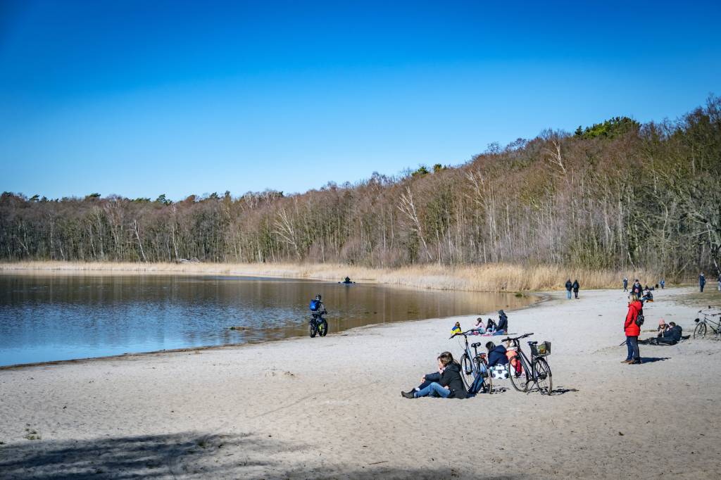 Menschen sitzen am Strand am See