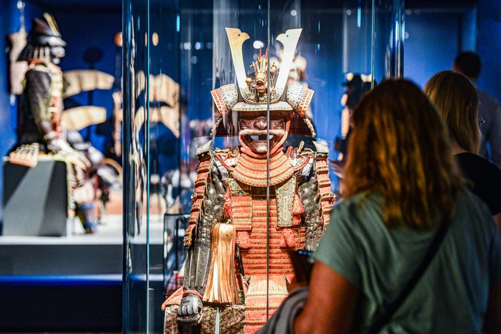 Frau sieht sich Samurai-Rüstung in Vitrine an